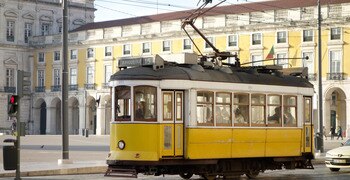 un tren amarillo que viaja por las vías del tren cerca de un edificio