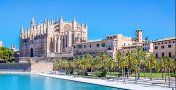 Un gran edificio de piedra con palmeras