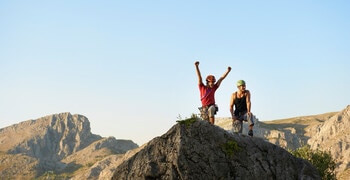 a group of people standing on a rock with a blue sky