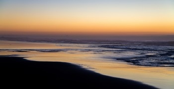 Una playa con olas y una puesta de sol