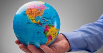 a hand holding a blue and yellow earth globe
