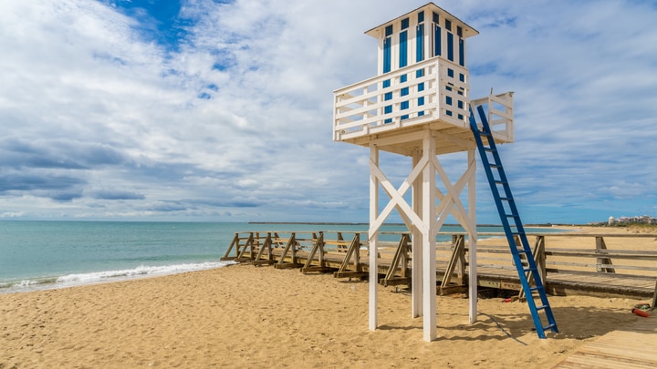 una persona sentada en la cima de una playa de arena
