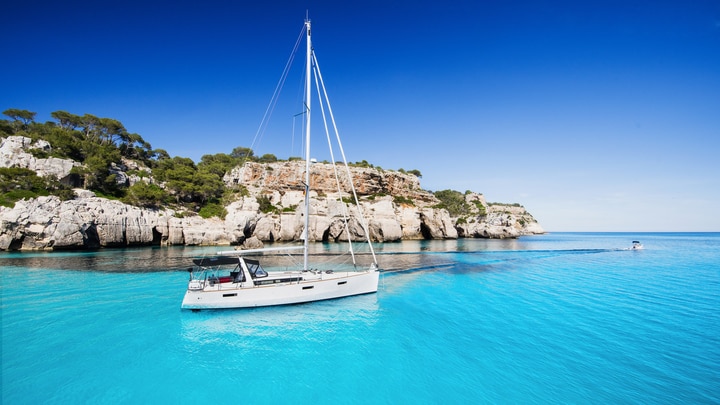 a blue and white boat sitting next to a body of water
