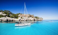 a blue and white boat sitting next to a body of water