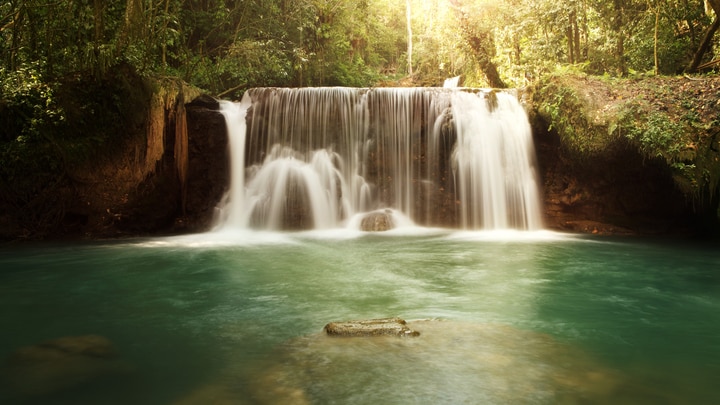 a waterfall cascading into the water in Jamaica